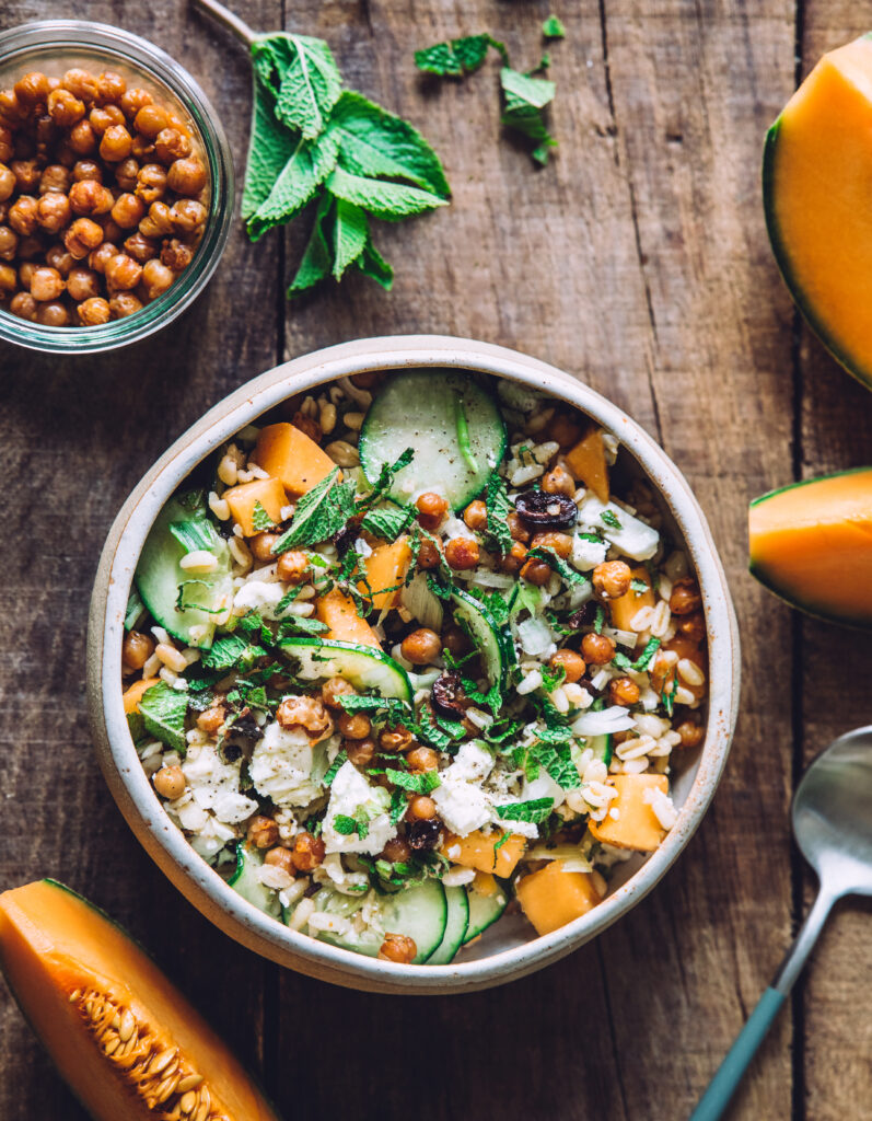 Composition asymétrique de photographie culinaire avec un bol de salade de fruits et légumes sur une table en bois.